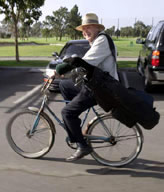 Golfer riding bike with clubs